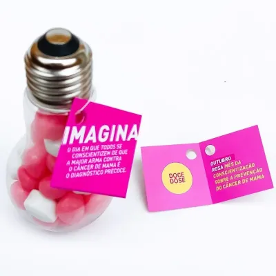 Brinde lâmpada com balas personalizadas para Outubro Rosa e tag com mensagem de conscientização sobre prevenção do câncer de mama.